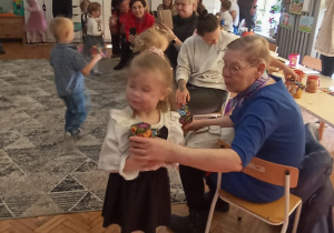 dziadkowie z wnuczkami ozdabiają lampiony zimowe