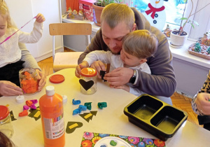 dziadkowie z wnuczkami ozdabiają lampiony zimowe