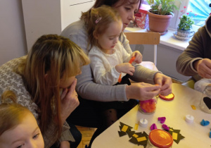 dziadkowie z wnuczkami ozdabiają lampiony zimowe