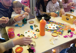 dziadkowie z wnuczkami ozdabiają lampiony zimowe