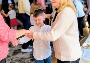 Dzieci tańczą w kole z dziadkami