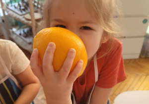 Dziewczynka trzyma pomarańczę w rękach