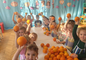 Dzieci podnoszą do góry pomarańcze i cytryny