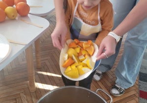 Chłopiec wrzuca pokrojone owoce do garnka