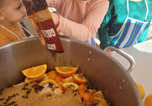 Dziewczynka wsypuje goździki do owoców