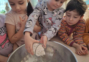 Dziewczynka wsypuje mąkę do miski