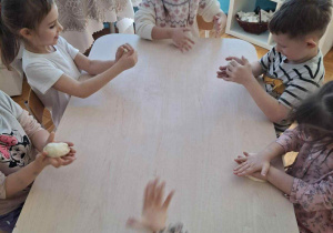 Dzieci przy stoliku rozgniatają masę solną