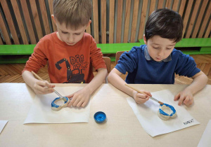 Chłopcy maluja na niebiesko świeczniki