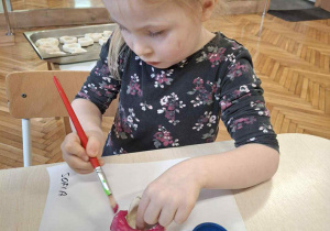 Dziewczynka maluje na różowo świecznik