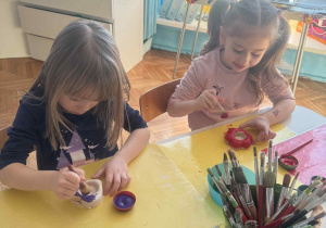 Dziewczynki malują świeczniki na fioletowo i różowo