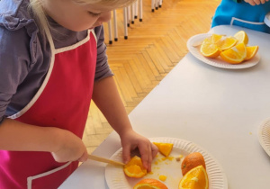 dzieci stojąw fartuszkach i kroją owoce