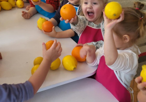 dzieci stojąw fartuszkach i kroją owoce
