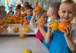 dzieci stojąw fartuszkach i kroją owoce