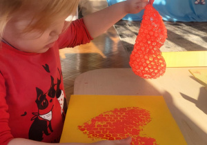 dziecko wykonuje pracę plastyczną, odkleja serce z folii bąbelkowej pozostawiając wzór serca na kartonie