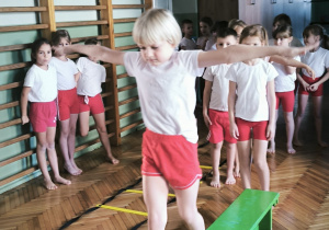 Chłopiec przechodzi po ławeczce z rękoma w bok