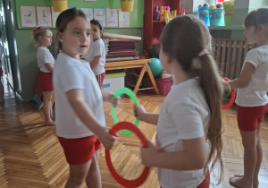 Dziewczynki stoją naprzeciwko siebie trzymając koła