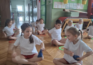 Dziewczynki siedza w siadzie skrzyżnym z woreczkami