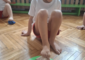 Chłopiec wkłada woreczek stopą do kółka