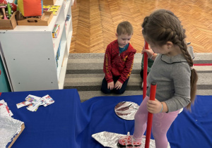 Dziewczynka ma na nogach narty z kijkami