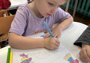 Dziewczynka kreśli znaki literopodobne