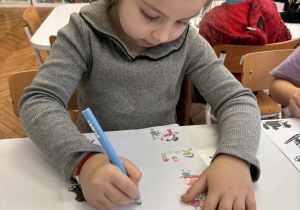 Dziewczynka niebieską kredką kreśli linie