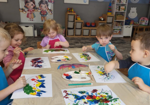 Dzieci siedza przy stole i robia stemple