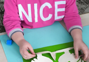 Dziewczynka nakleja łowicką wycinankę