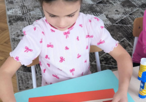 Dziewczynka nakleja łowickie koguciki