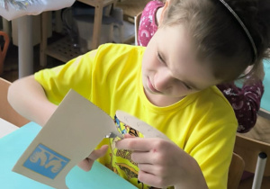 Dziewczynka nożyczkami wycina kokucika z papieru