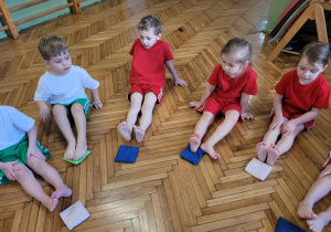 Dzieci z woreczkami połozonymi przed stopami