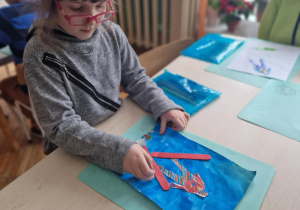 Dziewczynka przykleja patyczki jako narty