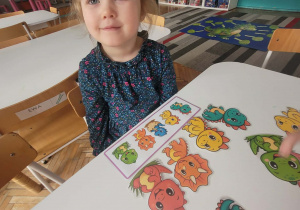 Dziewczybka układa ciągi z dinozaurami