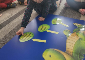 Dziewczynka uklada jajko dinozaura obok jego sylwety