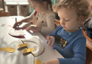 Chłopiec przykleja nogi dinozaura