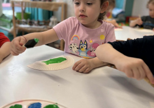 Dziewczynka maluje talerzyk na zielono