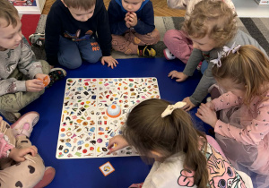Dzieci siedzą wokół planszy do gry w bystre oczko