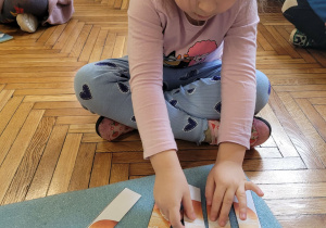 Dziewczynka układa puzzle na karimacie