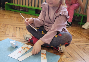 Dziewczynka patrzy na rozcięte paski puzzli