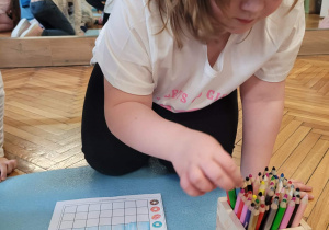 Dziewczynka wybiera kredkę z pudełka