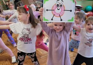 Dziewczynka pokazuje pączka w pozie, która robią inne dzieci