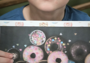 Chłopiec poakzuje kartę z pączkami