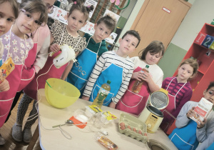 Dzieci stoją z produktami do zrobienia pączków