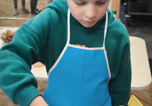 Chłopiec wkłada ciasto do frytownicy