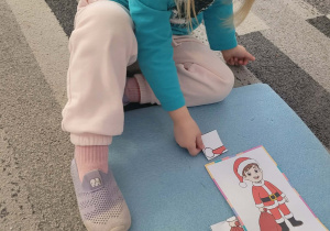 Dziewczyna przykłada element stroju Mikołaja