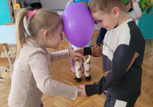 Dzieci trzymają balon czołem