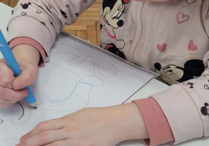 Dziewczynka niebieską kredką łączy kropki