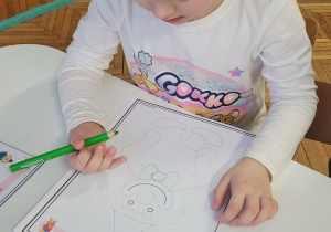 Dziewczynka zieloną kredką łączy kropki