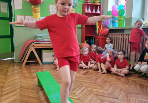 Dziewczynka idzie po zielonej ławce