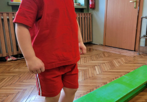 Dziewczynka przechodzi trzymając paluszkami u stóp rant ławki