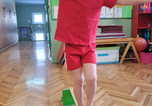 Chłopiec próbuje utrzymać równowagę na wąskiej ławce